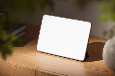 Ahşap masada boş ekran tableti, hafif ışıklandırma, bulanık ön plan. Modern çalışma alanı, dijital cihaz konsepti. 3B Hazırlama