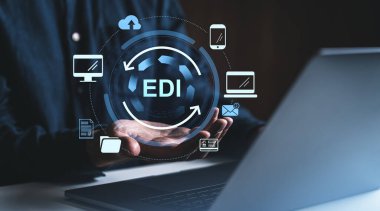Ellerinin üzerinde yüzen dijital EDI arayüzü olan bir bilgisayar kullanan bir işadamı, elektronik veri değişim teknolojisini sembolize ediyor