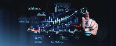 El, dijital ekrandaki fütüristik finansal verilerle ve analizlerle, karanlık arka planda parlayan arayüzle, iş zekası konseptiyle etkileşim halindedir.