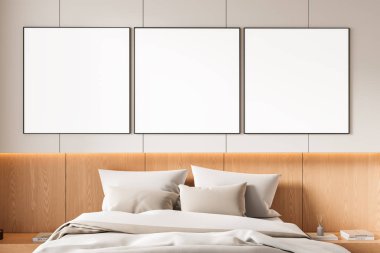 Yatağın üstündeki duvarda, rahat, modern yatak odasının içinde, ahşap panelde ve tarafsız arka planda, temiz, minimal tasarım tarzı üç boş poster var. 3B Hazırlama