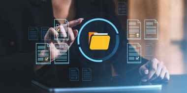 İş kadını, belge ve klasör simgelerine ulaşmak için fütürist dijital arayüz kullanıyor, karanlık arka planda modern veri yönetimi kavramı