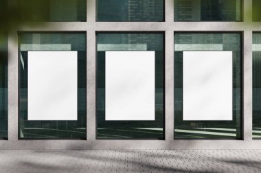 Modern cam duvarda üç boş poster modeli, temiz tasarım düzeni, beton zemin, şehir manzarası arka planı, açık hava reklamı konsepti. 3B Hazırlama