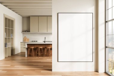 Modern mutfak içi ahşap bar tabureleri, bej dolaplar ve pencerenin yakınındaki temiz bir duvarda büyük boş bir poster çerçevesi.