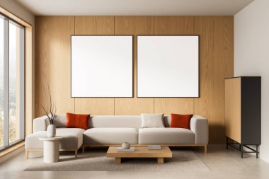 Çağdaş iç mekan, bej kanepenin üstündeki tahta duvarda iki boş poster altlığı, minimalist mobilyalar, nötr tonlar. 3B Hazırlama