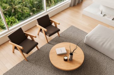 İki ahşap koltuğu, yuvarlak sehpası yumuşak dokuları ve geniş pencereli tropikal manzarası olan rahat modern iç mekan.