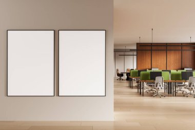 Modern ofis içindeki temiz bej bir duvarda, ahşap paneller ve yeşil çalışma yerlerinin yer aldığı iki boş poster modeli. 3B Hazırlama