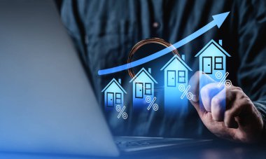 İşadamı, dijital yükselen ev simgelerine ve mavi arka planda yüzde işaretlerine sahip dizüstü bilgisayar kullanıyor, emlak piyasası ve yatırım büyümesi kavramı