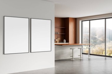 Modern bir iç mekanda, ahşap aksanlı mutfak ve geniş pencereli beyaz bir duvarda iki boş çerçeveli poster, temiz bir düzen konsepti. 3B Hazırlama