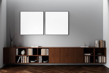 Ahşap dolabın üstündeki gri duvarda, içinde kitaplar ve dekorlar olan iki boş kare poster, minimalist odada modern iç tasarım konsepti. 3B Hazırlama