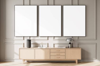 Ahşap dolabın üstünde üç boş poster, temiz duvar panelleri ve şık tasarım konseptiyle minimalist bir düzen. 3B Hazırlama