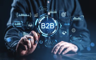 İşadamı dijital B2B arayüzü ile etkileşime girerek grafikleri ve veri analizlerini, fütürist grafik stilini, karanlık arkaplanı, dijital pazarlama kavramını gösterir