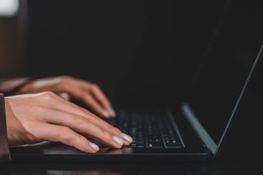 Close-up of womans hands typing on laptop keyboard, realistic photography style, dark blurred background, concept of productivity and technology