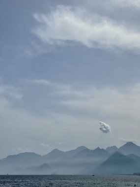 Dağların ve okyanusun üzerindeki bulutlu gökyüzü