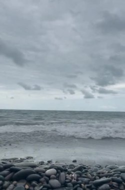 Dalgalı deniz kıyısı ve bulutlu gri gökyüzü