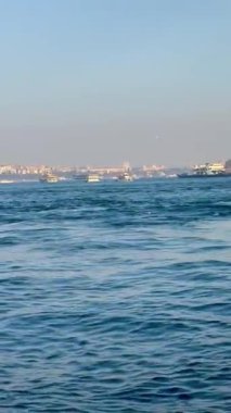 Mavi dalgalı deniz ve ufukta şehir