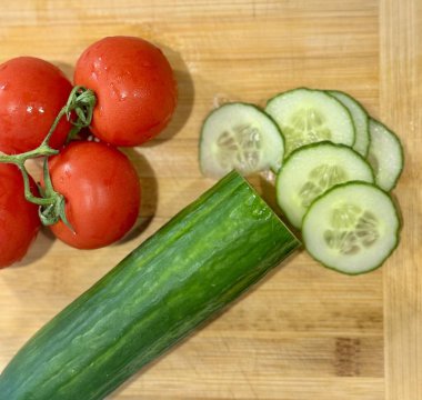 Salatalıklar ve domatesler kesim tahtasına yakın çekim.