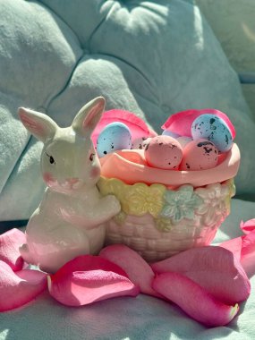 Dekoratif Paskalya tavşanı ve seramik sepette küçük renkli yumurtalar.