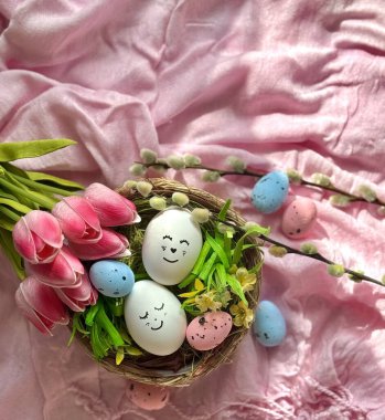 Paskalya yumurtaları pembe masa örtüsü üzerinde dekoratif bir sepetin içinde.