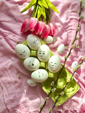 Altı Paskalya yumurtası ve pembe masa örtüsü üzerinde bir buket lale.