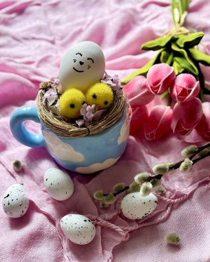 Süslü sepet mavi bardakta boyalı yumurta.