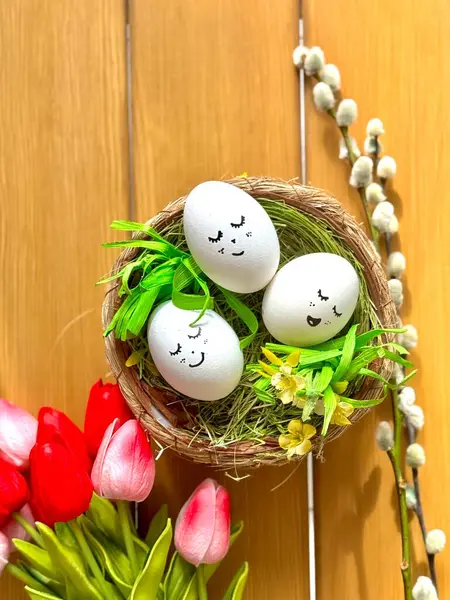 Sepette süslü yumurtalar, pembe laleler ve söğüt dalı.