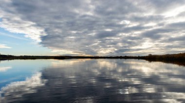 dramatik, zıt gökyüzü gölün yüzeyindeki yansımalarla ufuktaki karanlık ağaç siluetleri, sonbahar