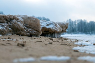 Deniz kıyısında buz parçaları, farklı boyutlarda buz sarkıtları, kum tepelerinde kum ve buz dokusu, Baltık Denizi, kışın Letonya