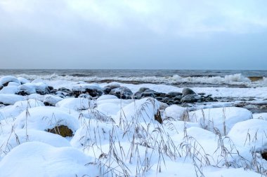Deniz kıyısındaki kayalar ve kumsallardaki çeşitli buz oluşumları, buz dokusu, rüzgar, su ve buz birlikte çalışıyor, kışın deniz kenarında.