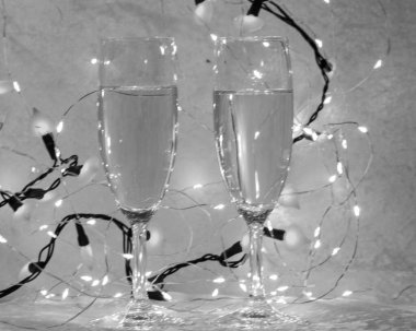 black and white still life with two champagne glasses, blurred spot lights background, holiday concept, free space for text, happy valentines day