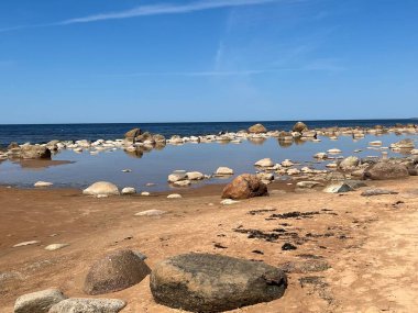 Güneşli deniz manzarası, mavi gökyüzü, deniz kıyısında birçok taş, Vidzeme kayalık kıyısı, Letonya