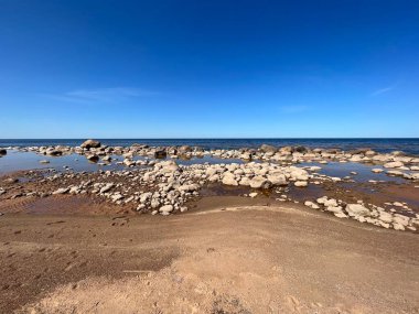 Güneşli deniz manzarası, mavi gökyüzü, deniz kıyısında birçok taş, Vidzeme kayalık kıyısı, Letonya