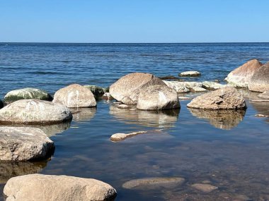 Güneşli deniz manzarası, mavi gökyüzü, deniz kıyısında birçok taş, Vidzeme kayalık kıyısı, Letonya