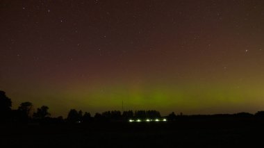 Aurora Borealis 'in devasa, çok renkli yeşil görüntüsü. Aurora Polaris, Letonya' da bir gölün üzerinde gece gökyüzünde kuzey ışıkları olarak da bilinir.