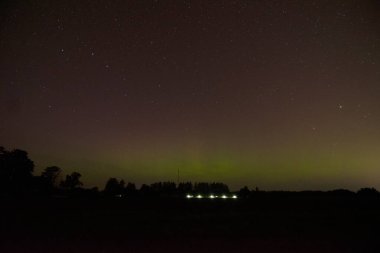 Aurora Borealis 'in devasa, çok renkli yeşil görüntüsü. Aurora Polaris, Letonya' da bir gölün üzerinde gece gökyüzünde kuzey ışıkları olarak da bilinir.