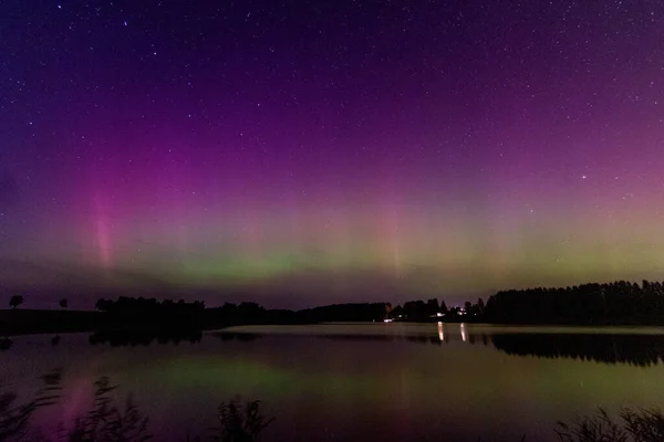 stock image night image of a massive multi-colored green vibrant Aurora Borealis, Aurora Polaris also known as the northern lights in the night sky over a lake, Latvia