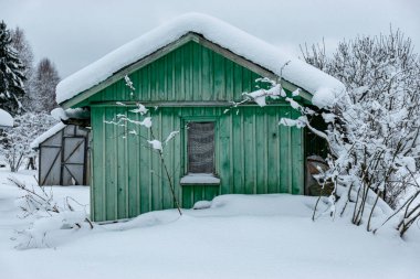 Kışın bahçe, karla kaplı, meyve ağaçları, bahçe evi ve bahçe aksesuarları, kışın küçük bahçe.