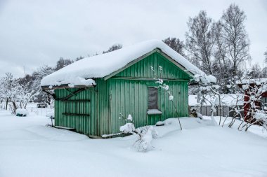 Kışın bahçe, karla kaplı, meyve ağaçları, bahçe evi ve bahçe aksesuarları, kışın küçük bahçe.