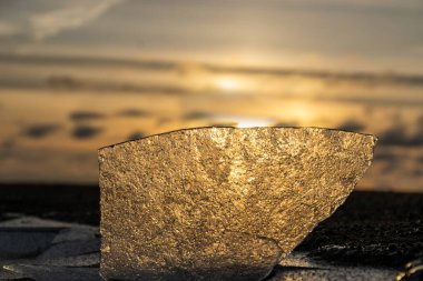 Deniz kıyısı olan kış manzarası, deniz kenarında gün batımı, deniz kıyısında buzla kaplı plaj.