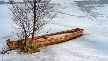 Buzun içinde donmuş ahşap bir kayıkla bahar manzarası gölün kıyısında terk edilmiş tekneler, kışın sonları, doğanın ilk baharları.