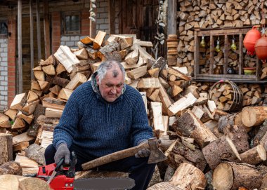 Bahçesinde baltayla çalışan bir adam kış mevsimi için yakacak odun, yakacak odun ve yakacak odun işliyor.