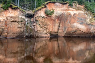 Nehir kıyısında kumtaşı kayalıkları, kumlu nehir kıyısı, geçen yılın çimenleri, yeşilliksiz doğa, ilkbahar başlarında Erglu kayalıkları, Cesu ilçesi, Letonya