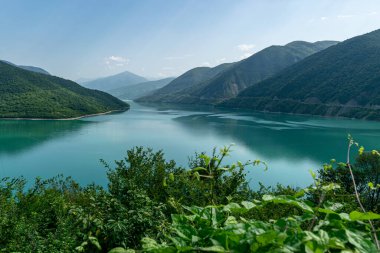 Küçük bir dağı ve parlak yeşil gölü olan güzel bir manzara, yaz.
