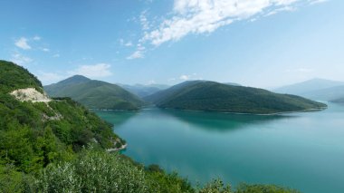 Küçük bir dağı ve parlak yeşil gölü olan güzel bir manzara, yaz.