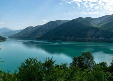 Küçük bir dağı ve parlak yeşil gölü olan güzel bir manzara, yaz.
