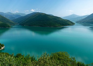 Küçük bir dağı ve parlak yeşil gölü olan güzel bir manzara, yaz.