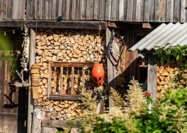 Çiçek ve bahçe eşyalarıyla süslenmiş odun yığını, kış için yakacak odun stoğu, bahçe süslemeleri, yaz zamanı