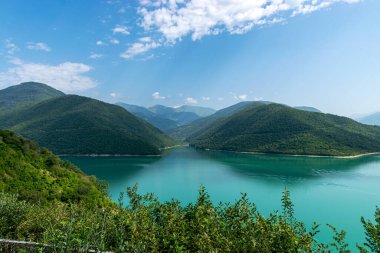 Küçük bir dağı ve parlak yeşil gölü olan güzel bir manzara, yaz.