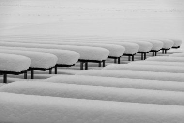 Beyaz kış günü, kalın bir kar örtüsüyle kaplı ahşap banklar, ışık ve gölge oyunları, ritim