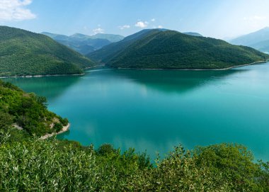 Küçük bir dağı ve parlak yeşil gölü olan güzel bir manzara, yaz.