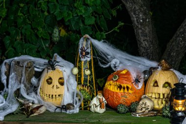 Alışılmadık orjinal Cadılar Bayramı kompozisyonu, korkutucu Jack O Lantern Cadılar Bayramı balkabakları, farklı yüzlerle oyulmuş balkabakları farklı Cadılar Bayramı süslemeleriyle çevrili.